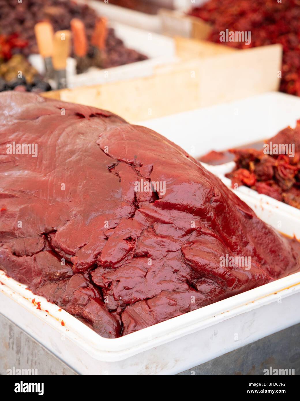 Lo Strattu è una pasta di pomodoro estremamente densa, scura e ricca di umami, ottenuta disidratando pura di pomodoro fresca con sale. Foto Stock