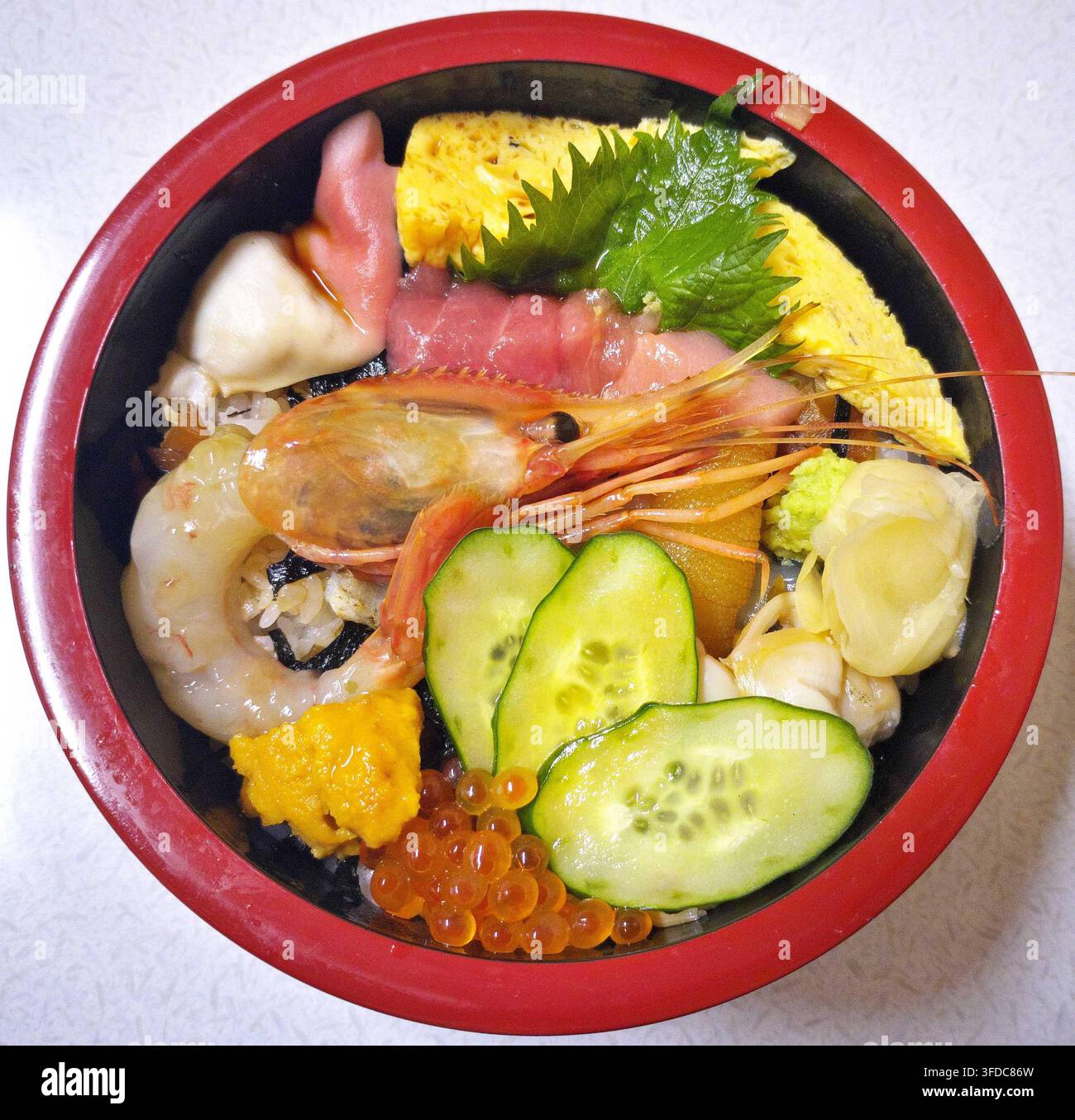 Deliziosa ciotola di riso giapponese chirashizushi con frutti di mare, gamberetti freschi, tonno, riccio di mare, uova di salmone e cetriolo, servita in una ciotola rotonda. Foto Stock
