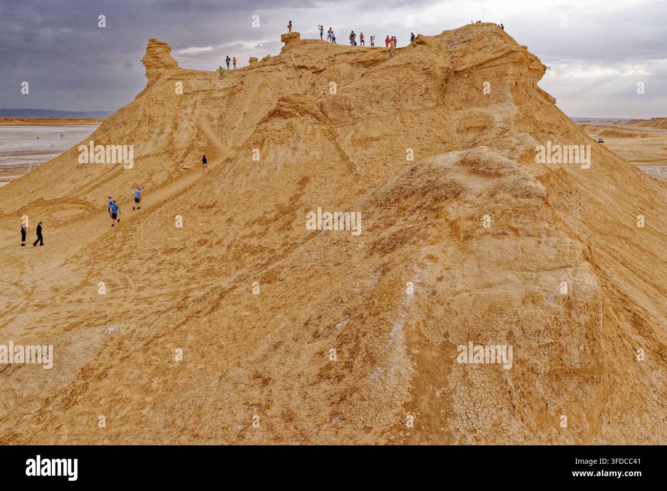 Vista di un gruppo di turisti che scalano la cresta della famosa formazione calcarea Camel Rock sotto un cielo nuvoloso a Ong Jmal, Tunisia. Fotografato il 0 Foto Stock
