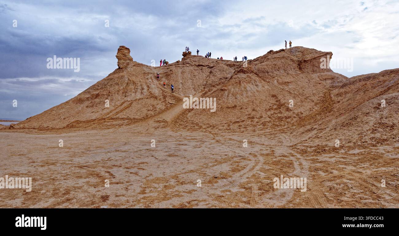Vista di un gruppo di turisti che scalano la cresta della famosa formazione calcarea Camel Rock sotto un cielo nuvoloso a Ong Jmal, Tunisia. Fotografato il 0 Foto Stock