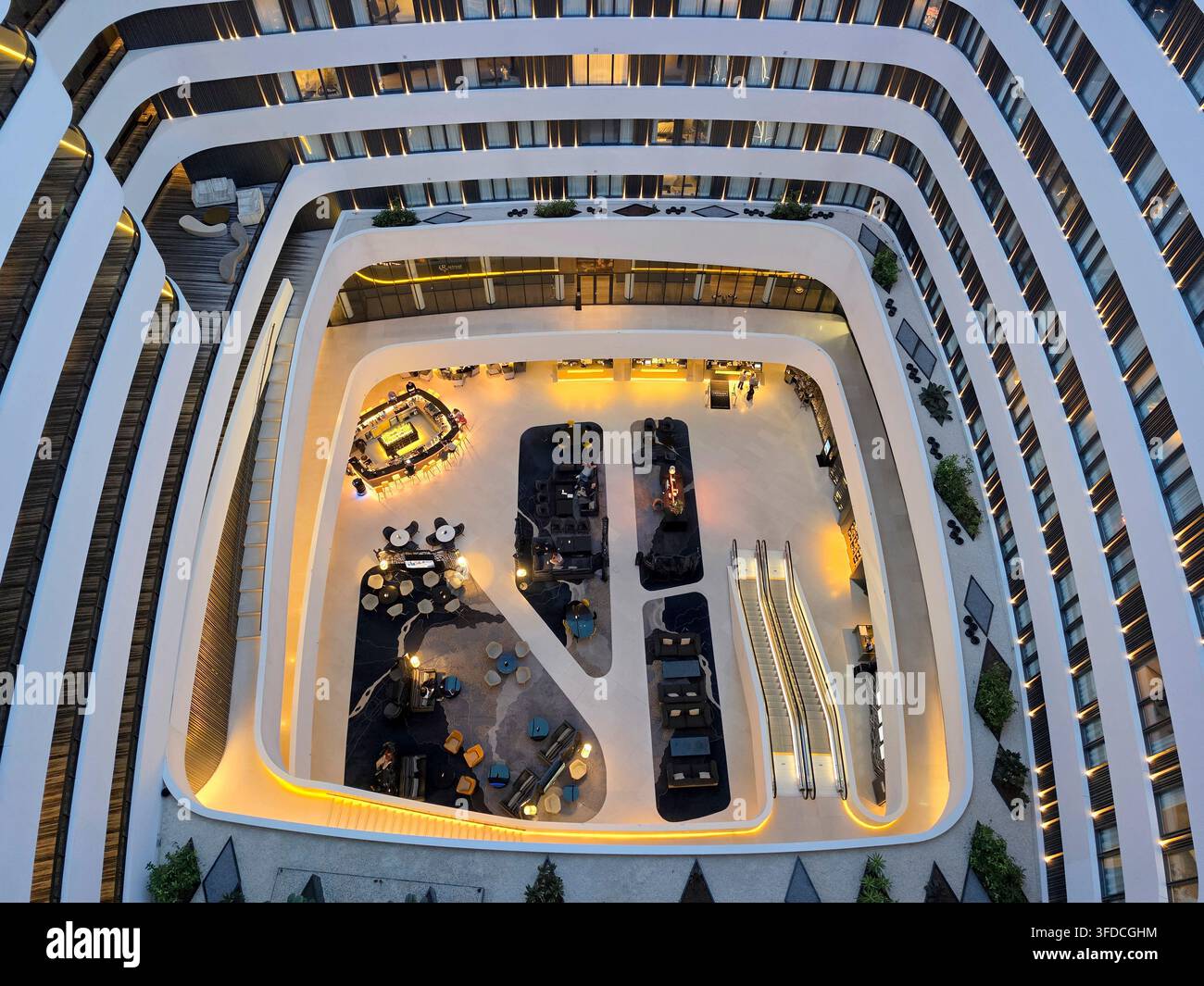 Interno moderno: atrio dell'hotel visto dall'alto, con vista sulle scale mobili e la lobby Foto Stock