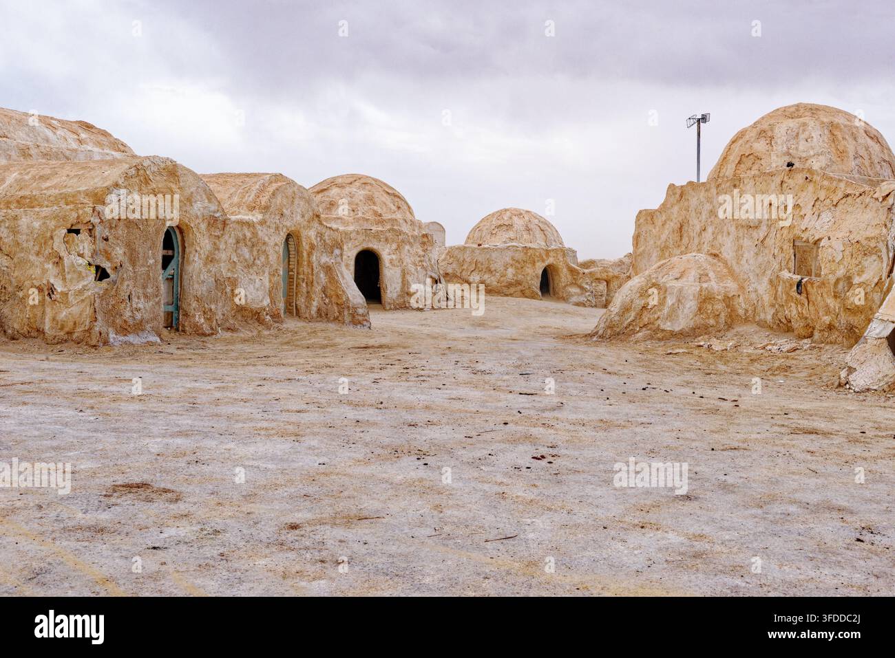 Vista stradale del deserto del luogo di ripresa abbandonato di Mos Espa per Star Wars, con strutture tradizionali a cupola sotto un cielo nuvoloso in Tunisia. Scatto Foto Stock