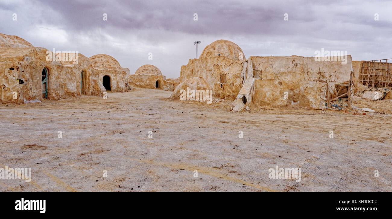 Vista stradale del deserto del luogo di ripresa abbandonato di Mos Espa per Star Wars, con strutture tradizionali a cupola sotto un cielo nuvoloso in Tunisia. Scatto Foto Stock