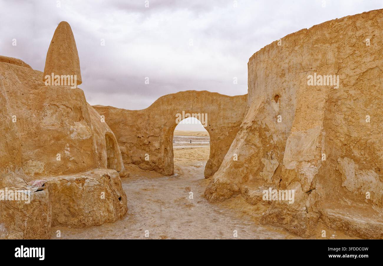 Vista attraverso un arco tradizionale in mattoni di fango incorniciato da edifici a cupola in gesso curvo nel set cinematografico abbandonato di Mos Espa in Tunisia. Catturato su Foto Stock