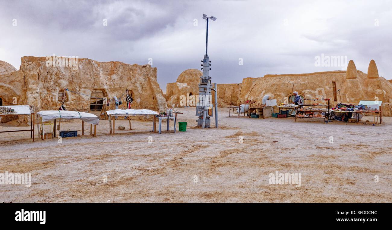 Banchi dei venditori di souvenir locali allineati davanti agli edifici intonacati con fango al set di Star Wars di Mos Espa ad Hammat-al-Jarid. Captur Foto Stock
