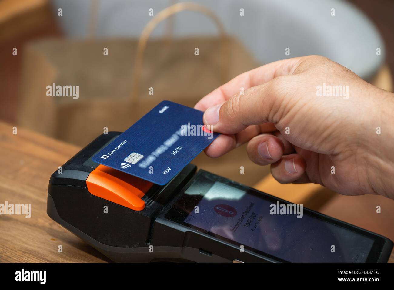 Una mano posiziona una carta di pagamento contactless blu su un terminale POS che mostra un messaggio di timeout di transazione rifiutata sul suo schermo. Foto Stock
