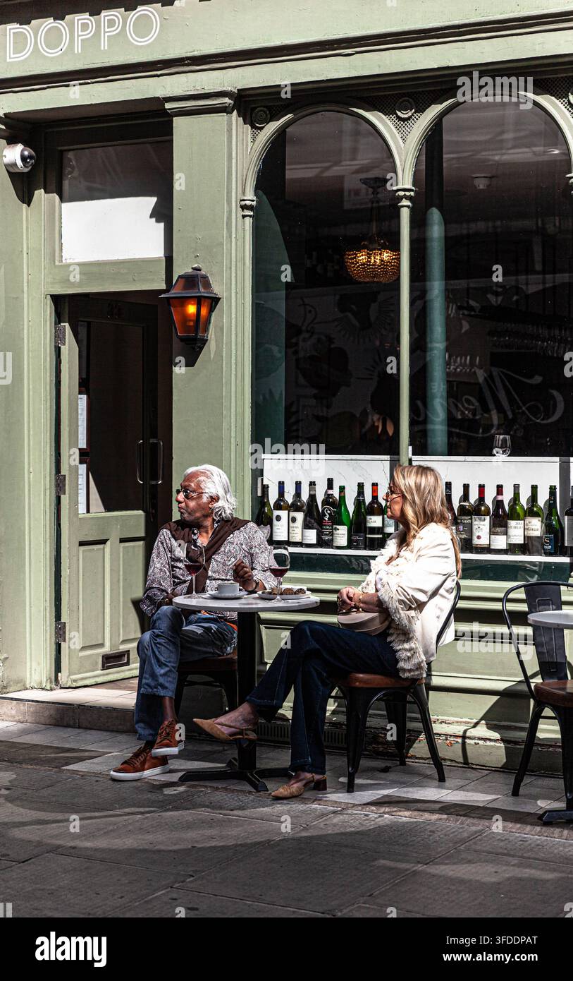 Una coppia multirazziale seduta fuori da un ristorante, Central London, Inghilterra, Regno Unito. Foto Stock