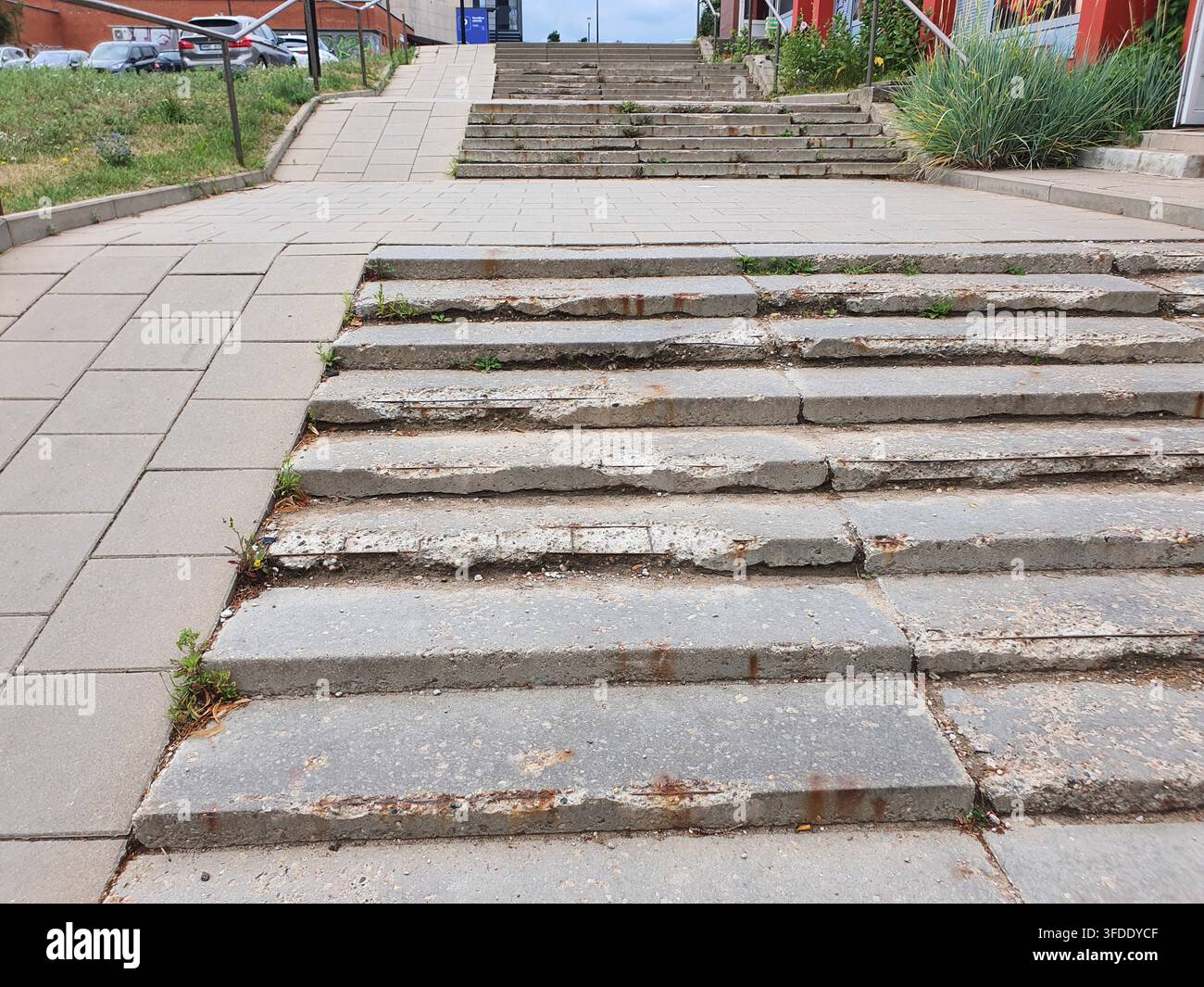 Vista ravvicinata di scale di cemento consumate e danneggiate in un ambiente urbano, che mostrano un deterioramento significativo con superfici crepate e gradini rotti Foto Stock