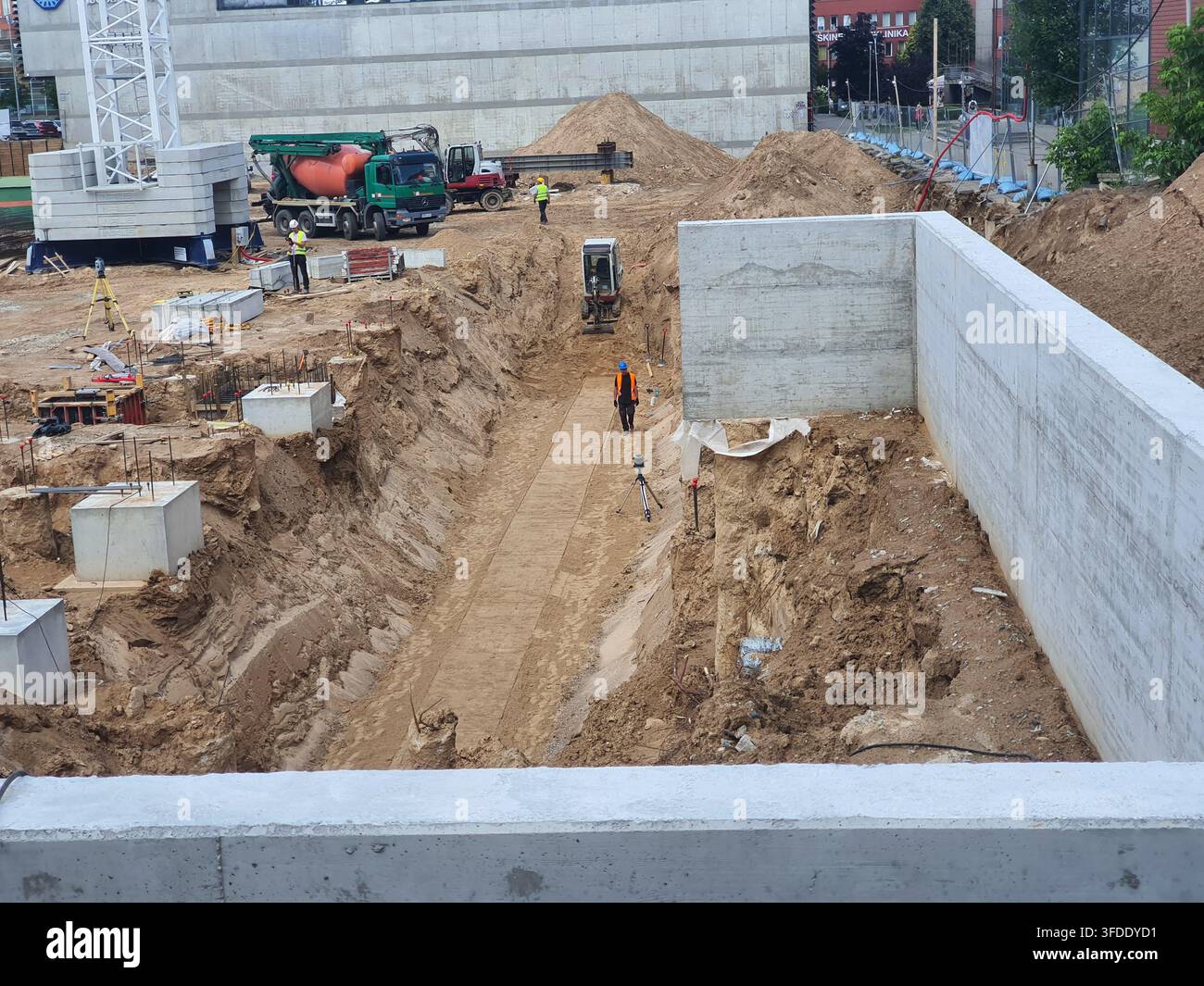 Vista aerea di un cantiere edile attivo con una trincea scavata in profondità che attraversa il centro, delimitata da muri di fondazione in cemento gettato Foto Stock