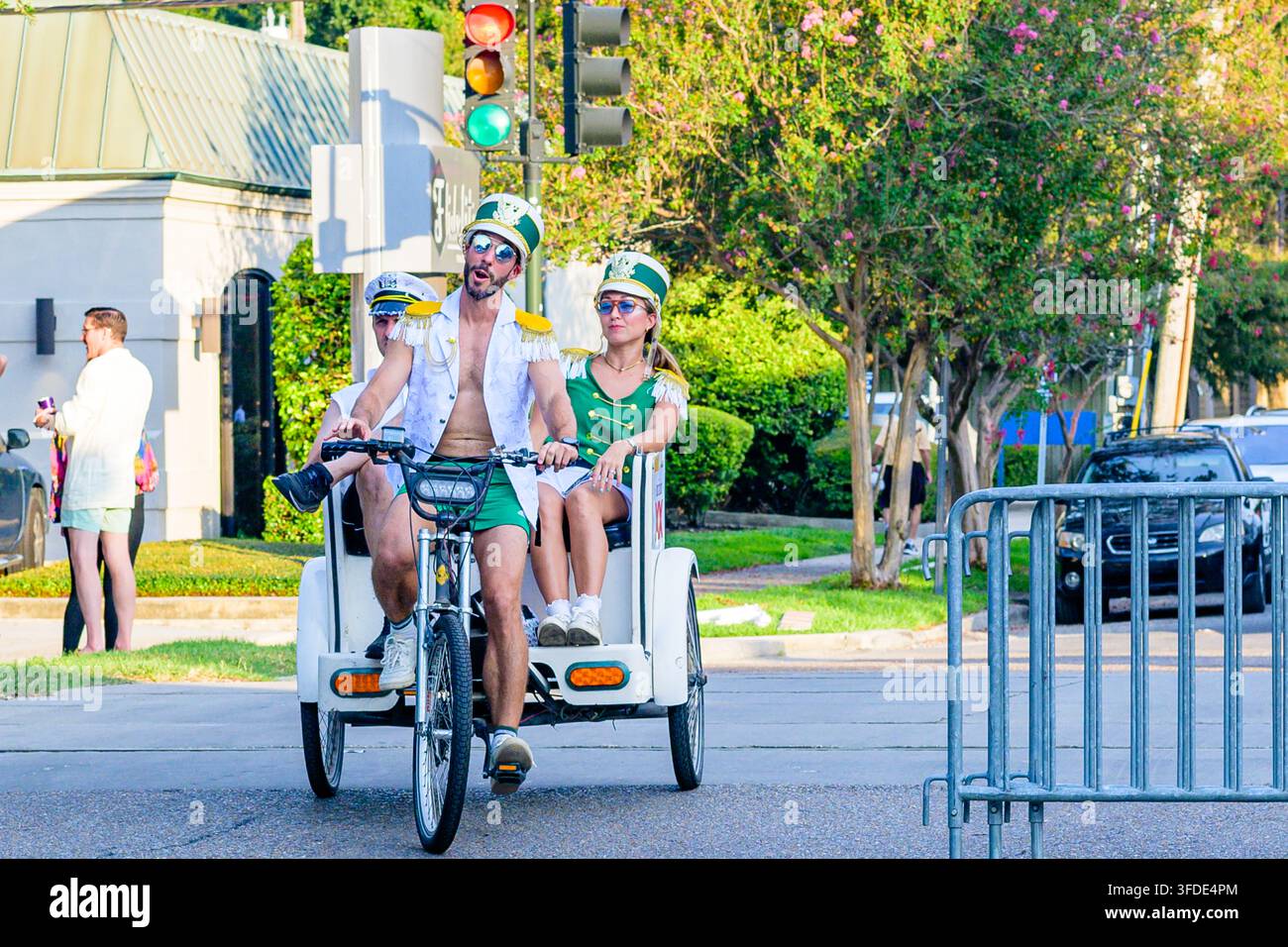 New Orleans, LA, USA - 29 agosto 2026: Tre persone in costume su un pedicab in direzione della celebrazione del Midsummer Mardi Gras all'incrocio tra Carrollton Avenue e Oak Street Foto Stock