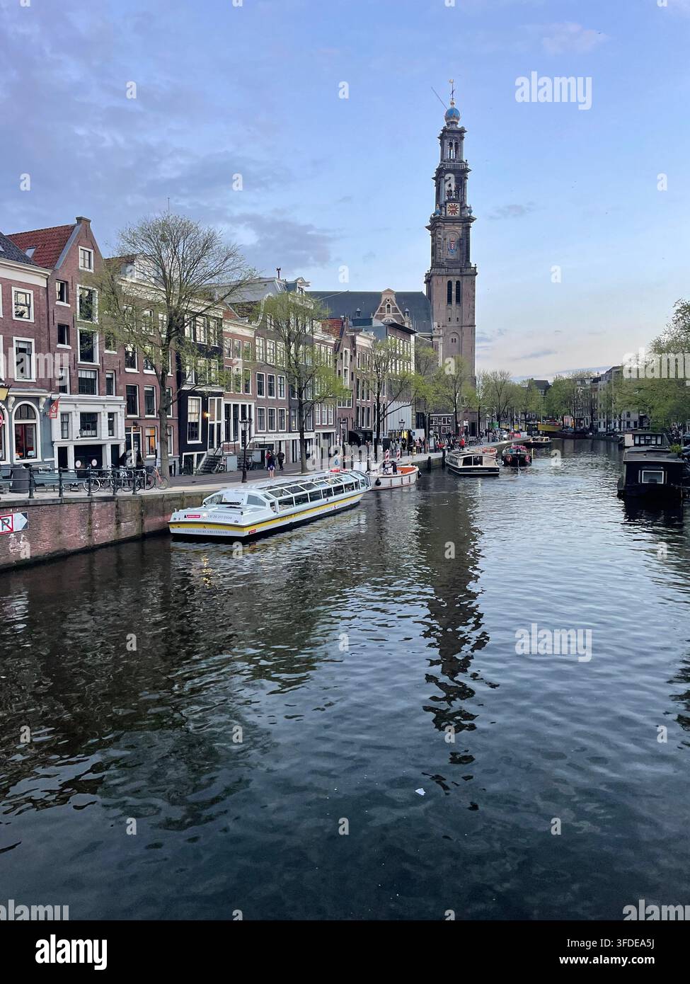 Una barca turistica sul canale è ormeggiata lungo le rive del canale Prinsengracht, vicino alla Westerkerk, nella comunità Joraan di Amsterdam Foto Stock