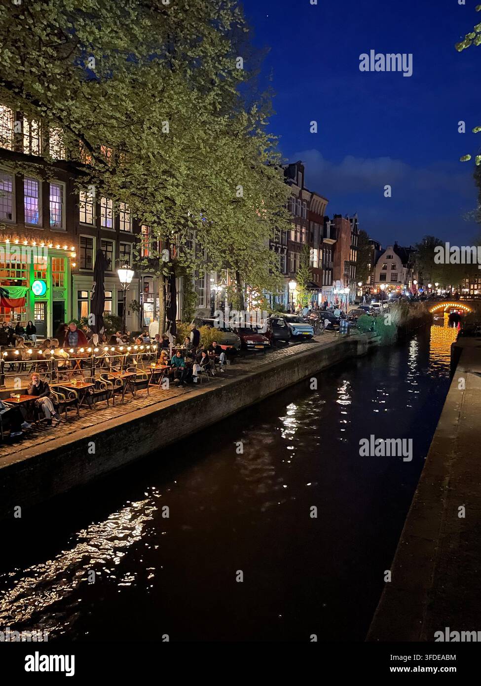 Una vivace scena notturna si svolge lungo il canale storico Prinsengracht del quartiere Jordaan in estate Foto Stock