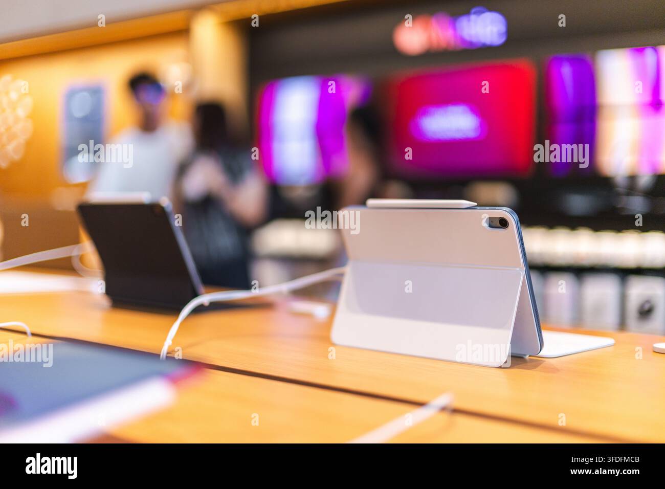 Computer tablet su tavolo espositivo in legno con acquirenti sfocati Foto Stock