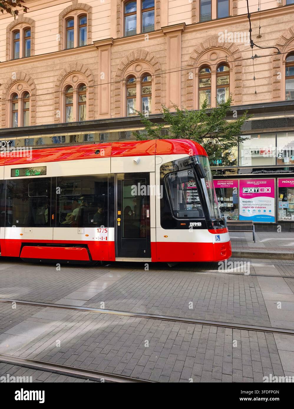 Brno, Repubblica Ceca – 29 agosto 2026: Un moderno tram a piano basso rosso e bianco Škoda ForCity della compagnia di trasporto pubblico DPMB attraversa l'historico - Immagine stock catturata con smartphone