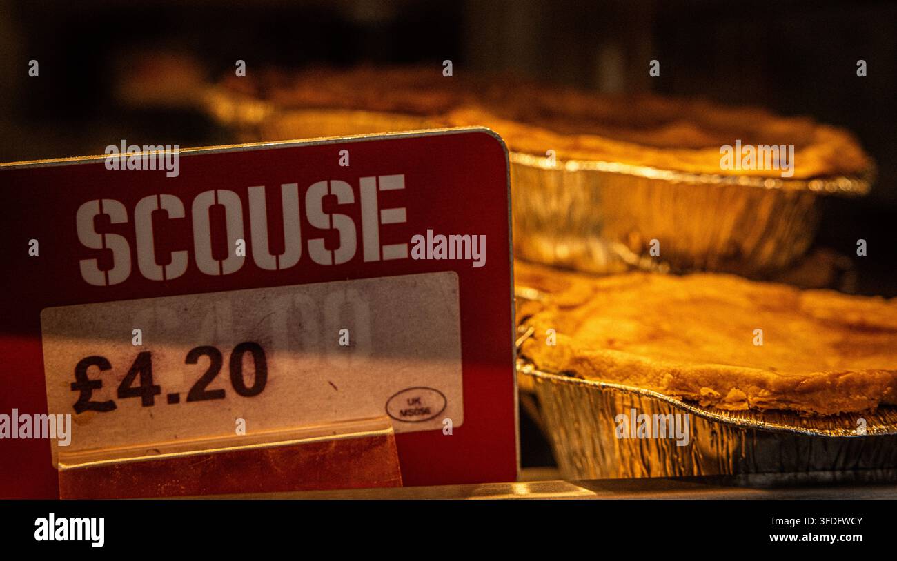 Torta britannica al prezzo di £4,20 all'interno di una vetrina di esposizione alimentare, con un'etichetta di prezzo rossa prominente che mostra la parola "SCOUSE". Foto Stock