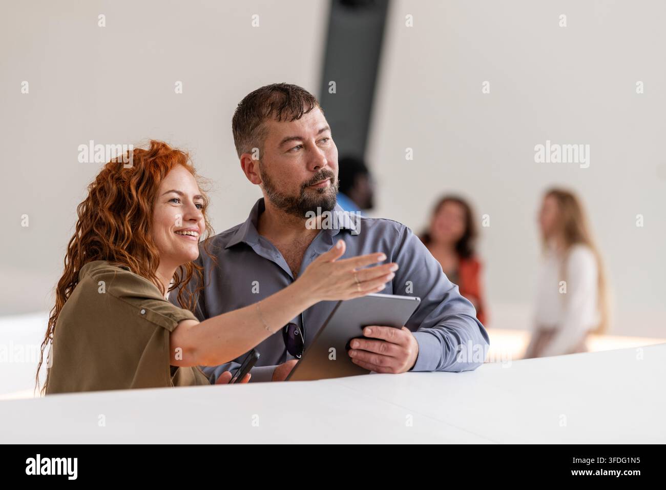 Donna sorridente indica qualcosa a un uomo con un tablet Foto Stock