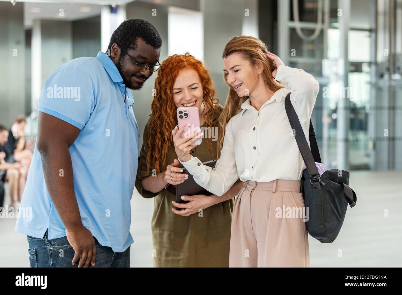 Diversi amici di lavoro che ridono insieme davanti a uno smartphone Foto Stock