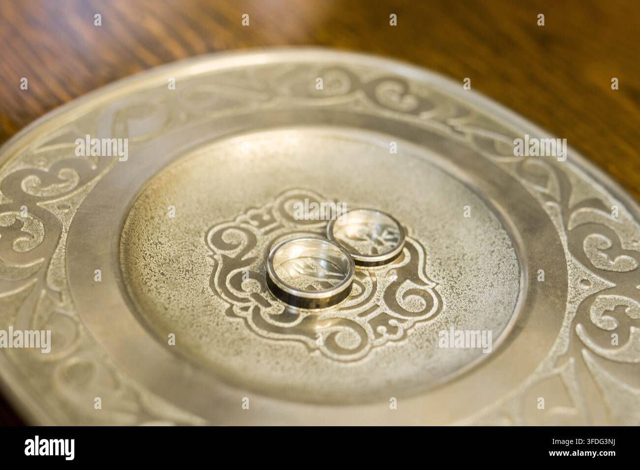 Due fedi nuziali poggiate su un piatto decorativo Foto Stock
