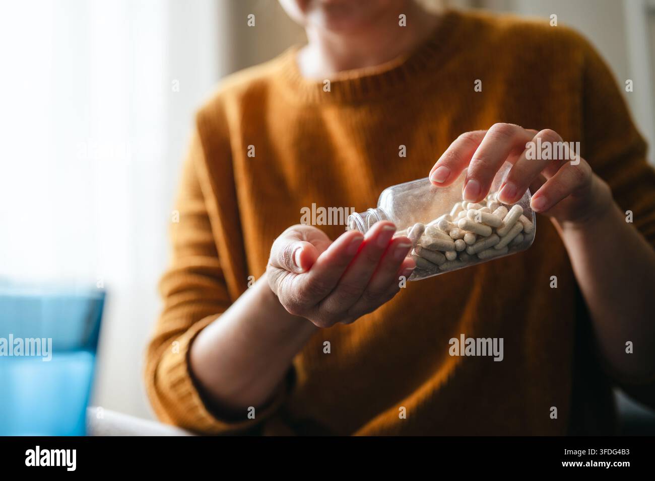 Donna che versa capsule di integratore nella propria mano Foto Stock