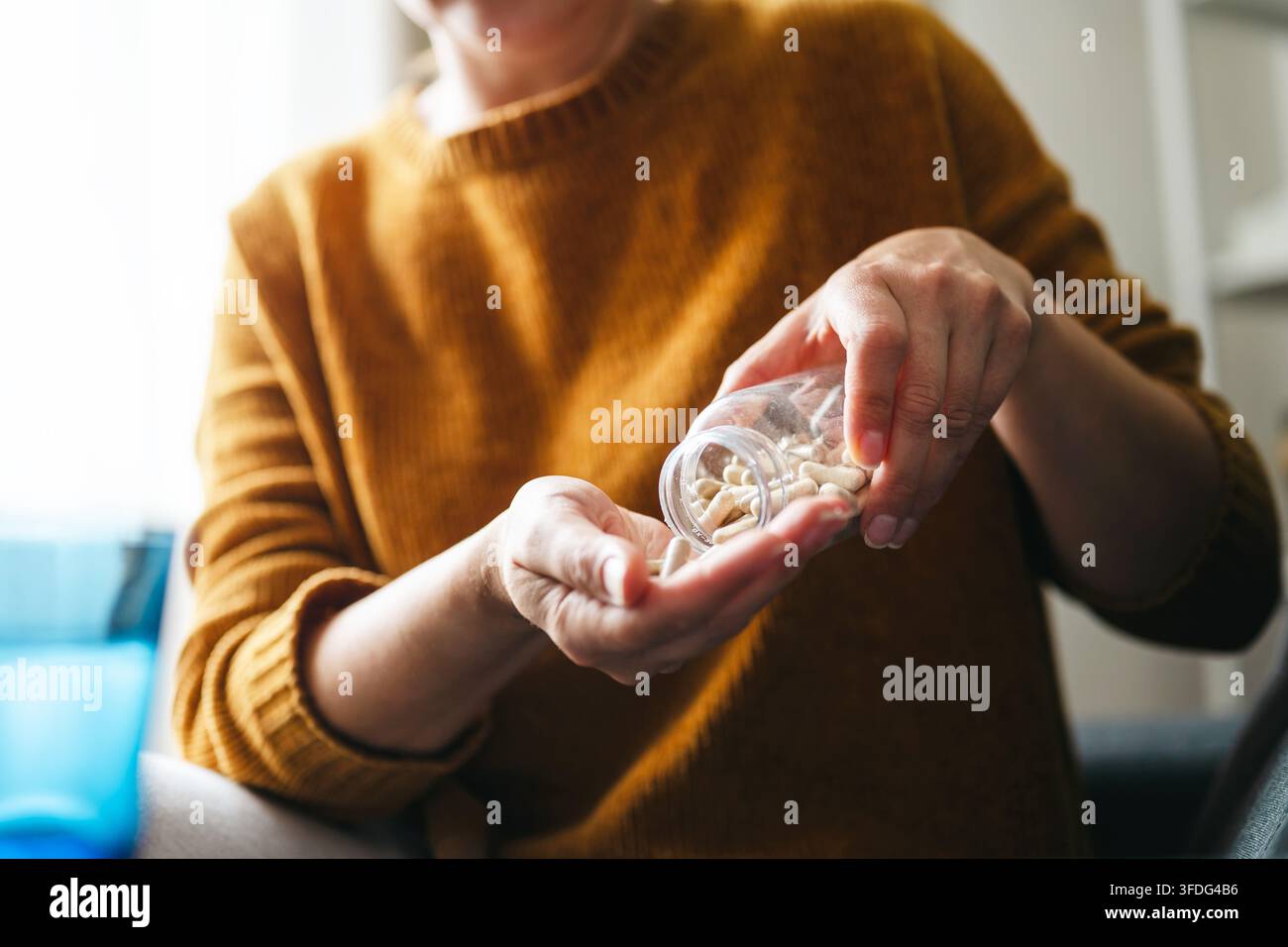 Donna che versa capsule di integratore nella propria mano Foto Stock
