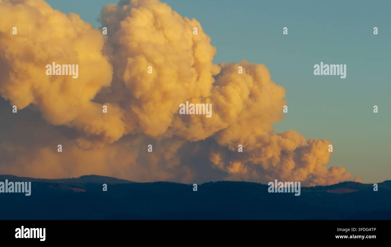 Il fumo degli incendi si alza sulle montagne al tramonto Foto Stock