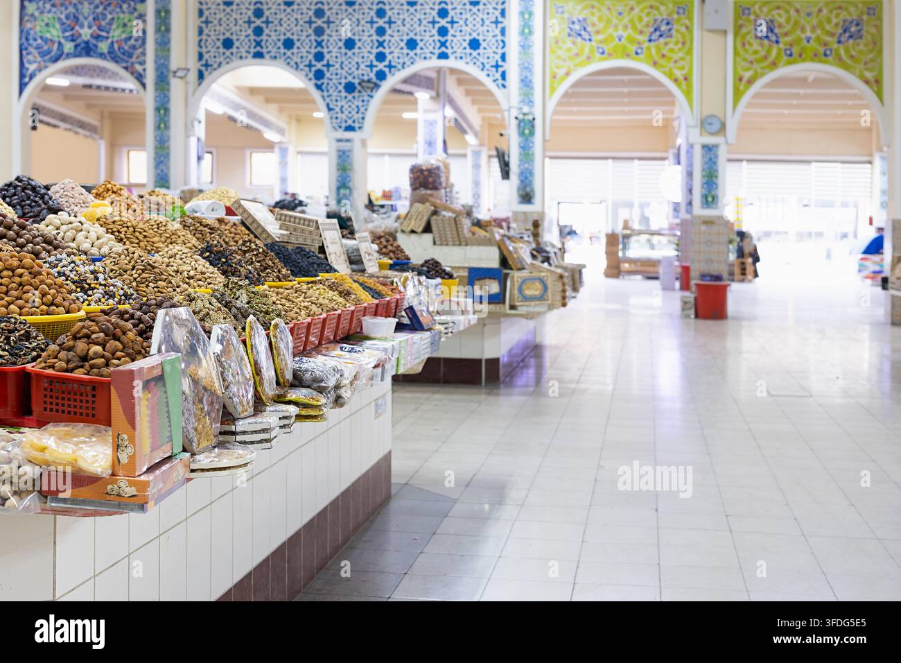 Frutta secca e noci esposte in mucchi in un bazar interno a Bukhara, Uzbekistan. Archi ornamentali con mosaici di piastrelle colorate incorniciano il spazioso m Foto Stock