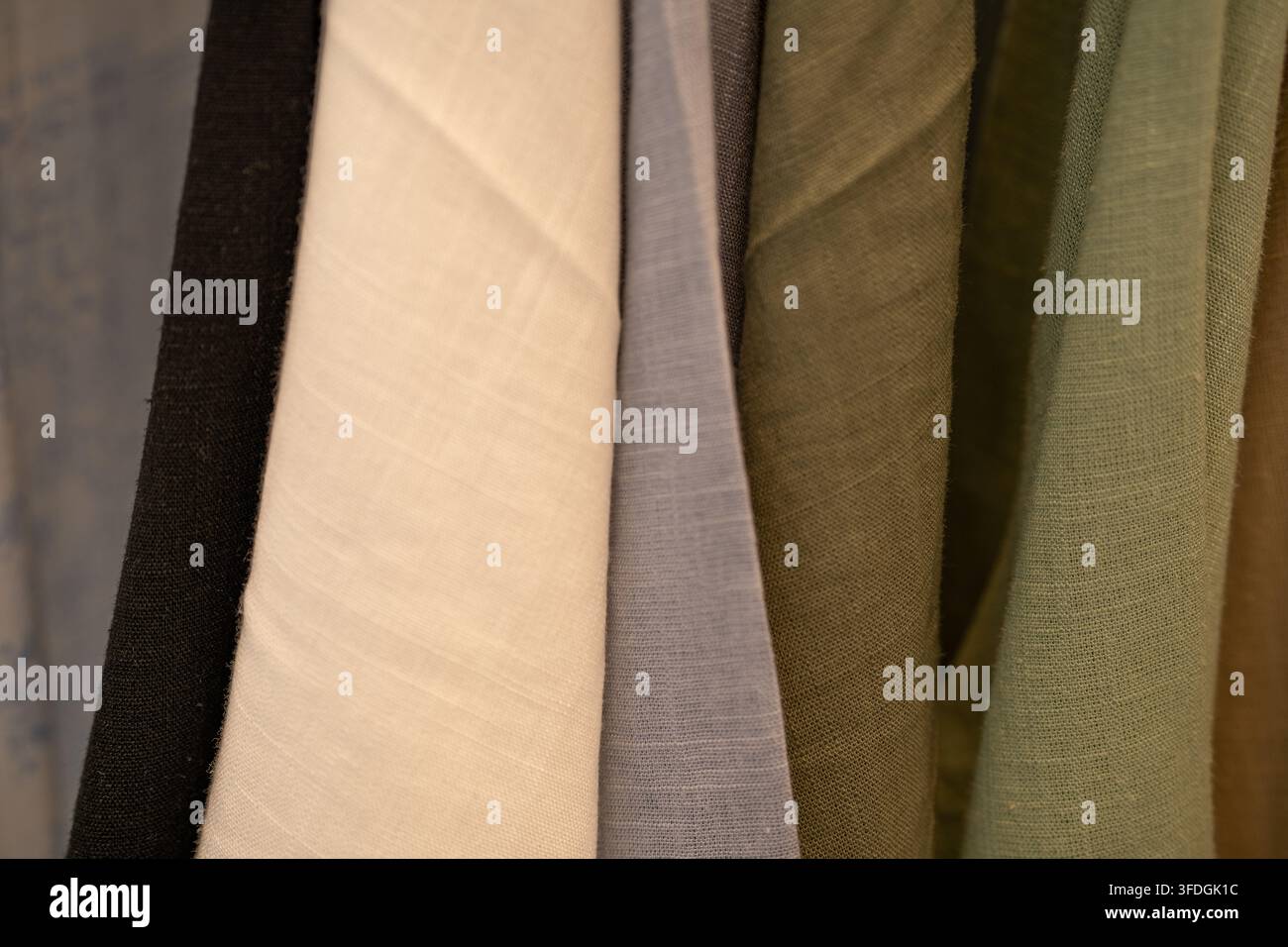 Primo piano di campioni di tessuto neutri appesi in uno studio di moda. Texture tessile naturale. Design di abbigliamento sostenibile, approvvigionamento etico e produzione consapevole Foto Stock