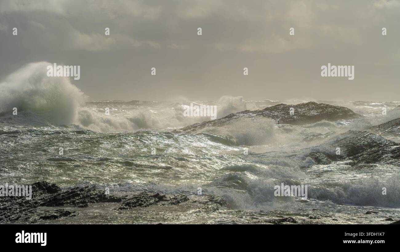 La turbolenza ondulatoria a strati riempie una scena rocciosa del Mare del Nord vicino a Langesund, in Norvegia, mentre più onde si alzano nella calda luce della tempesta per una forza naturale, marina Foto Stock