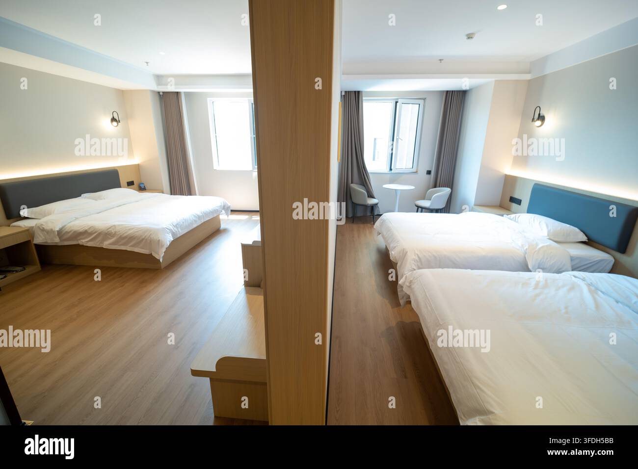 Suite moderna di hotel divisa in due aree letto con letti puliti e illuminazione calda. Foto Stock
