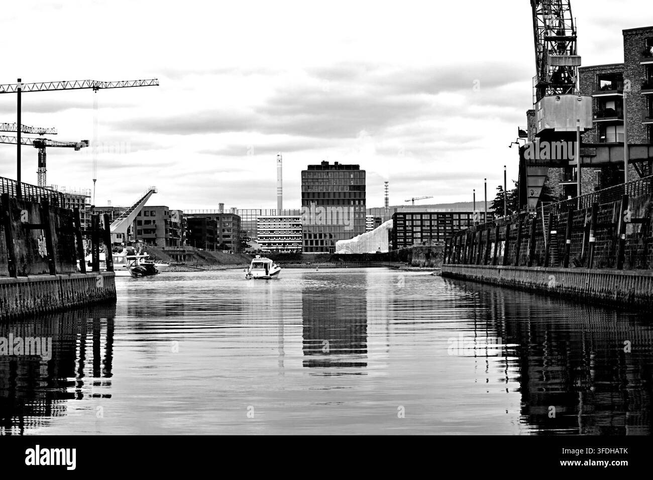 Mainz, Renania-Palatinato, Germania. Vista in bianco e nero del porto di Mainz con gru, bacino portuale e architettura urbana moderna. Foto Stock