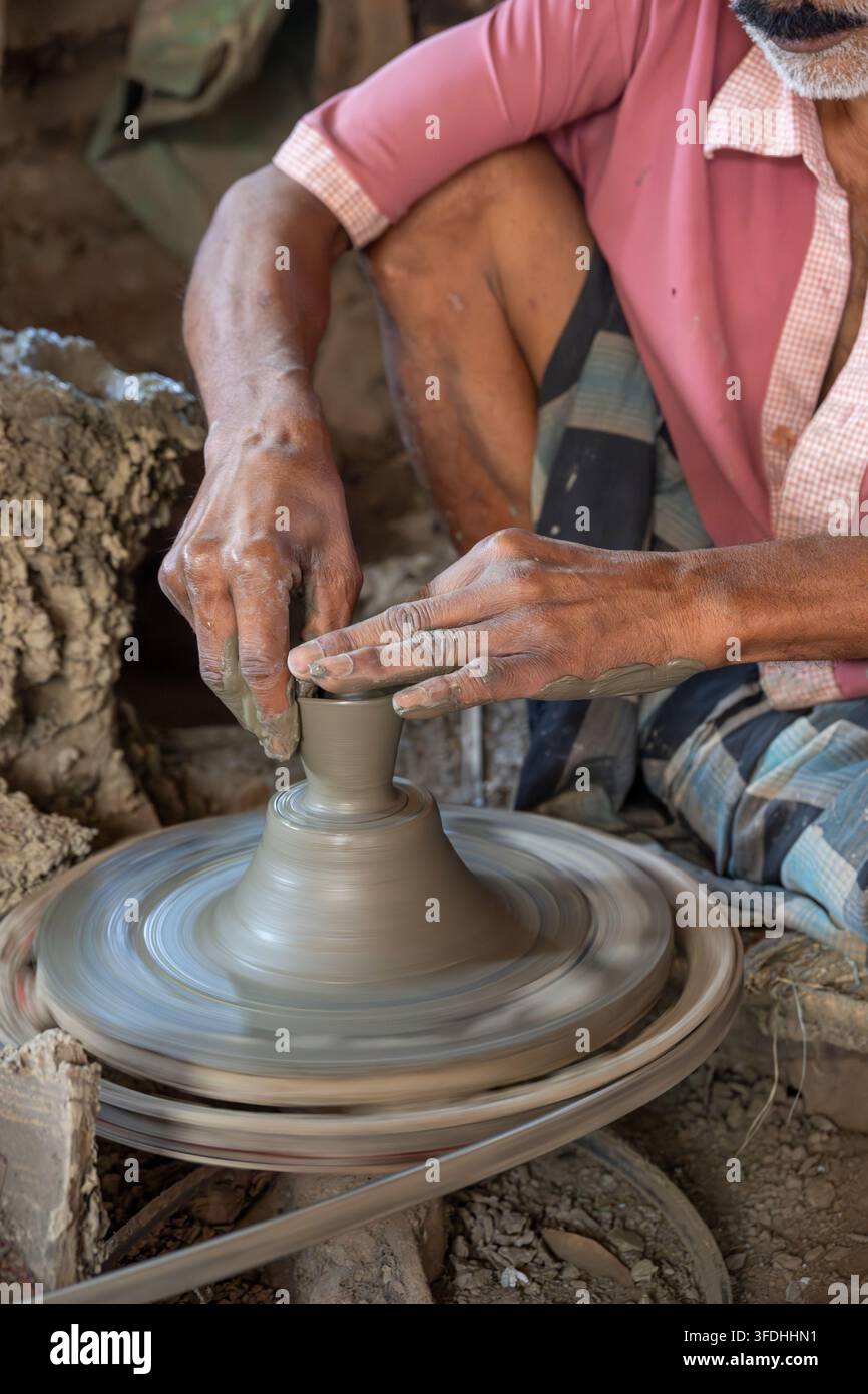 Un artigiano modella meticolosamente argilla bagnata su un tornio da vasaio, dimostrando antica arte ceramica e abilità manuale Foto Stock