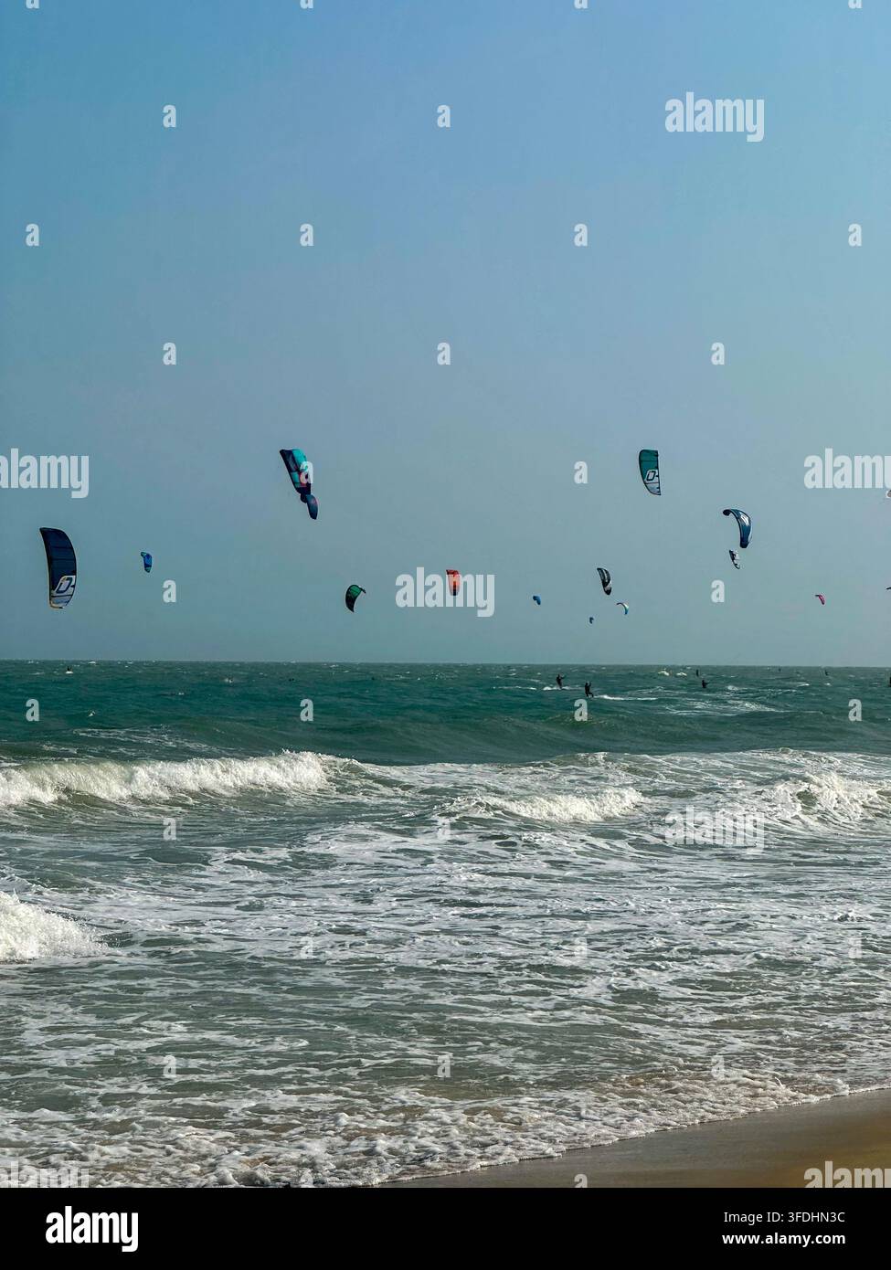 Azione dinamica di kitesurfing sulle onde dell'oceano con aquiloni colorati nel cielo. Uno scatto d'azione ampio di kitesurfer che cavalcano le onde dell'oceano sotto un cielo sereno, feat - Immagine stock catturata con smartphone