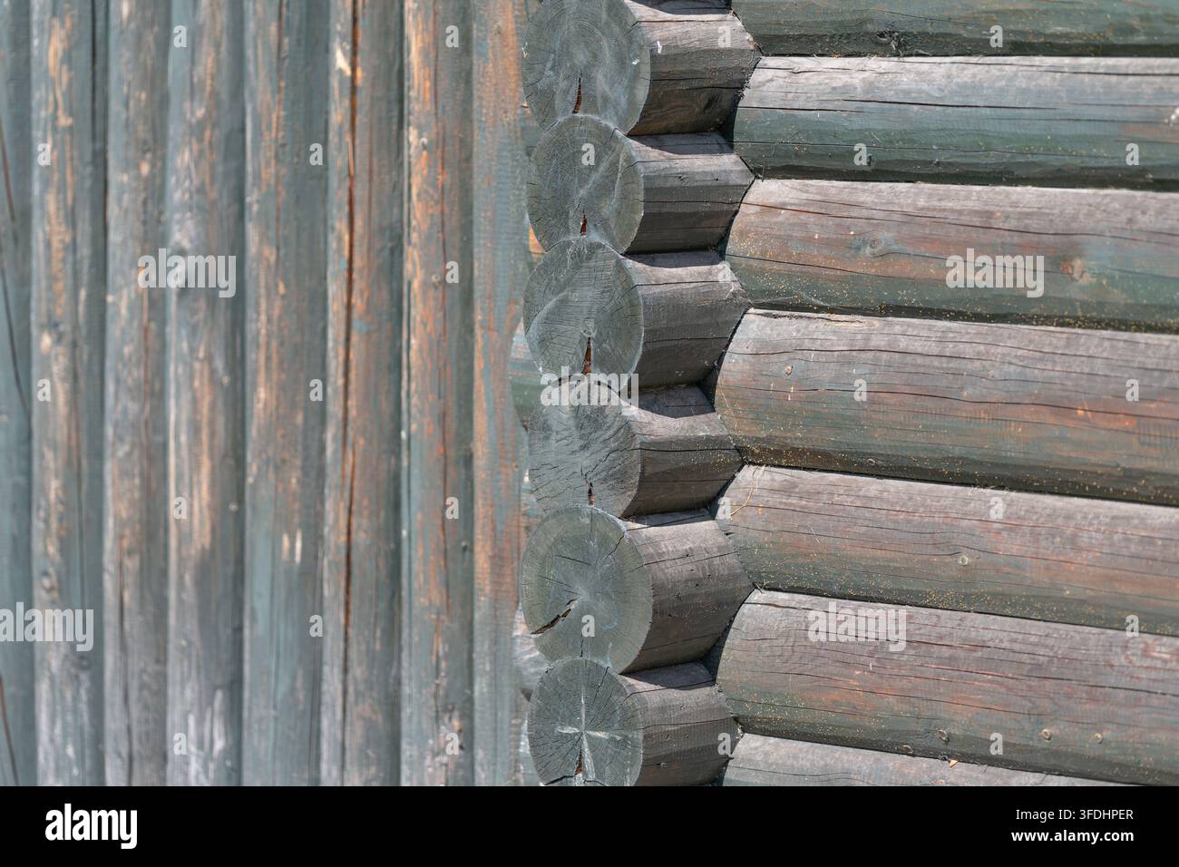 Il solido muro di una vecchia capanna di legno rivela giunti e trame unici dei tronchi. La luce del sole gioca sulla superficie esaltando la bellezza rustica di questo monte Foto Stock