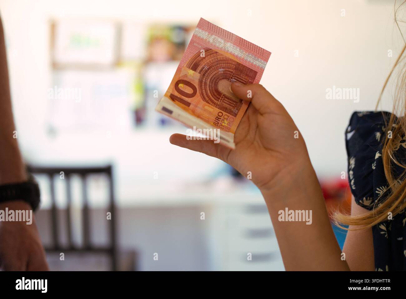 Mano di un bambino che tiene una banconota in euro, impara sull'economia e sul risparmiare Foto Stock