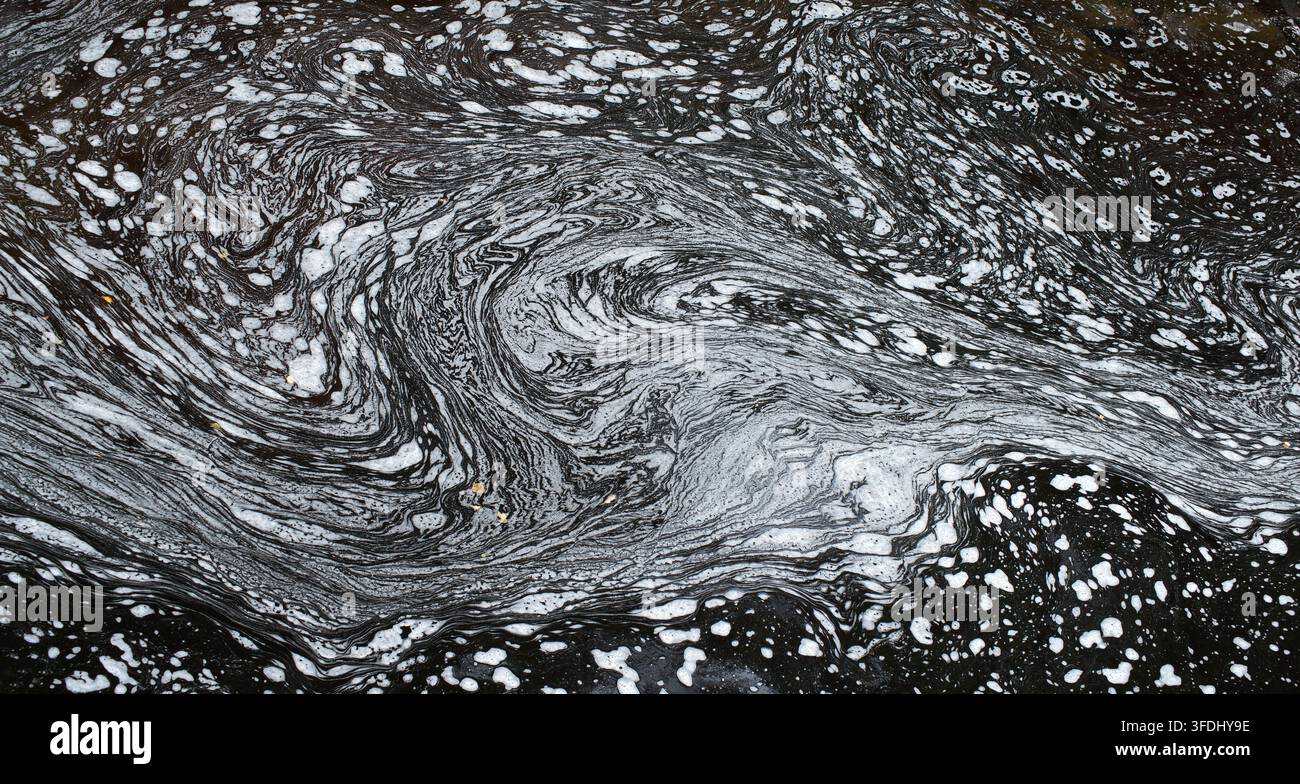 Immagini astratte suggestive in quasi monocromo che mostrano grandi forme ampie e curve create da bolle e schiuma nell'acqua che scorre Foto Stock
