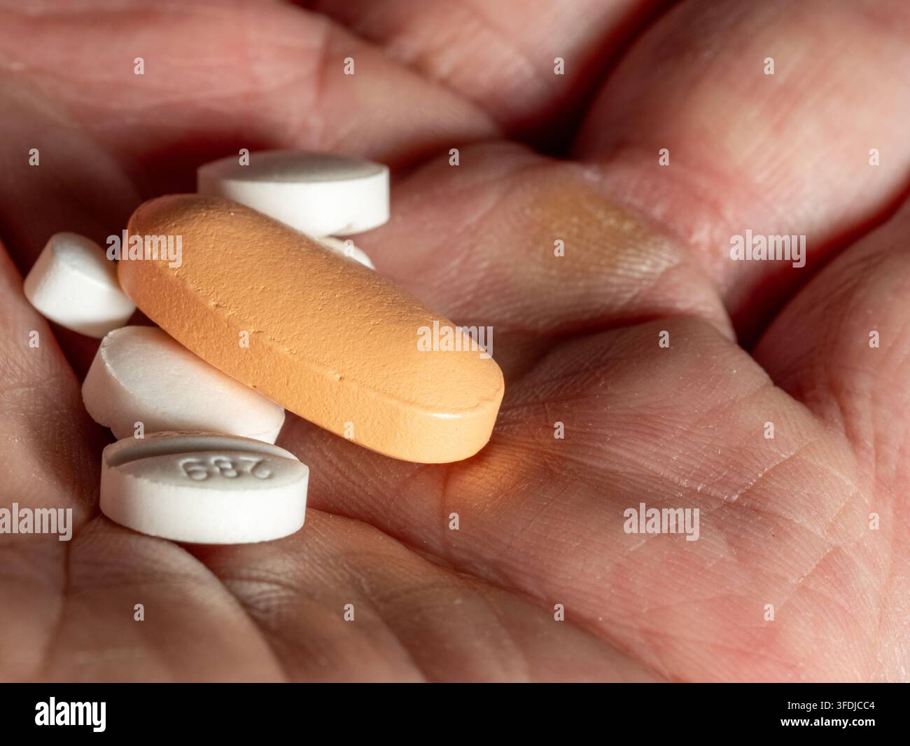 Primo piano di un palmo che tiene pillole e compresse miste, che trasmette temi di medicazione, assistenza sanitaria e trattamento su prescrizione per l'invecchiamento, il dosaggio, la cura personale Foto Stock