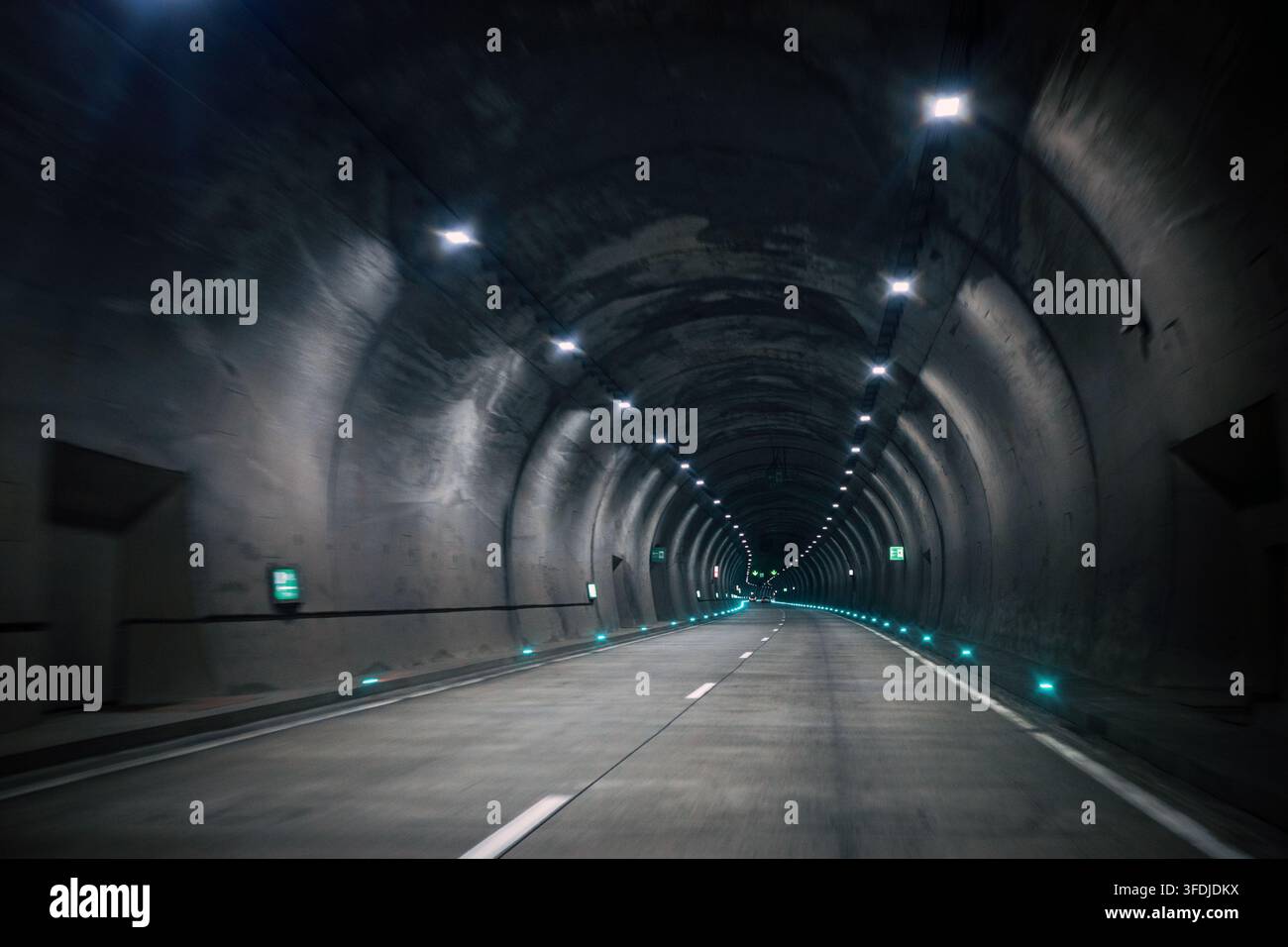 Corridoio del tunnel di sicurezza d'emergenza con luci di guida illuminate su strada curva, infrastruttura moderna per l'evacuazione, il monitoraggio, il trasporto sicuro e la mobilità resiliente. Foto Stock