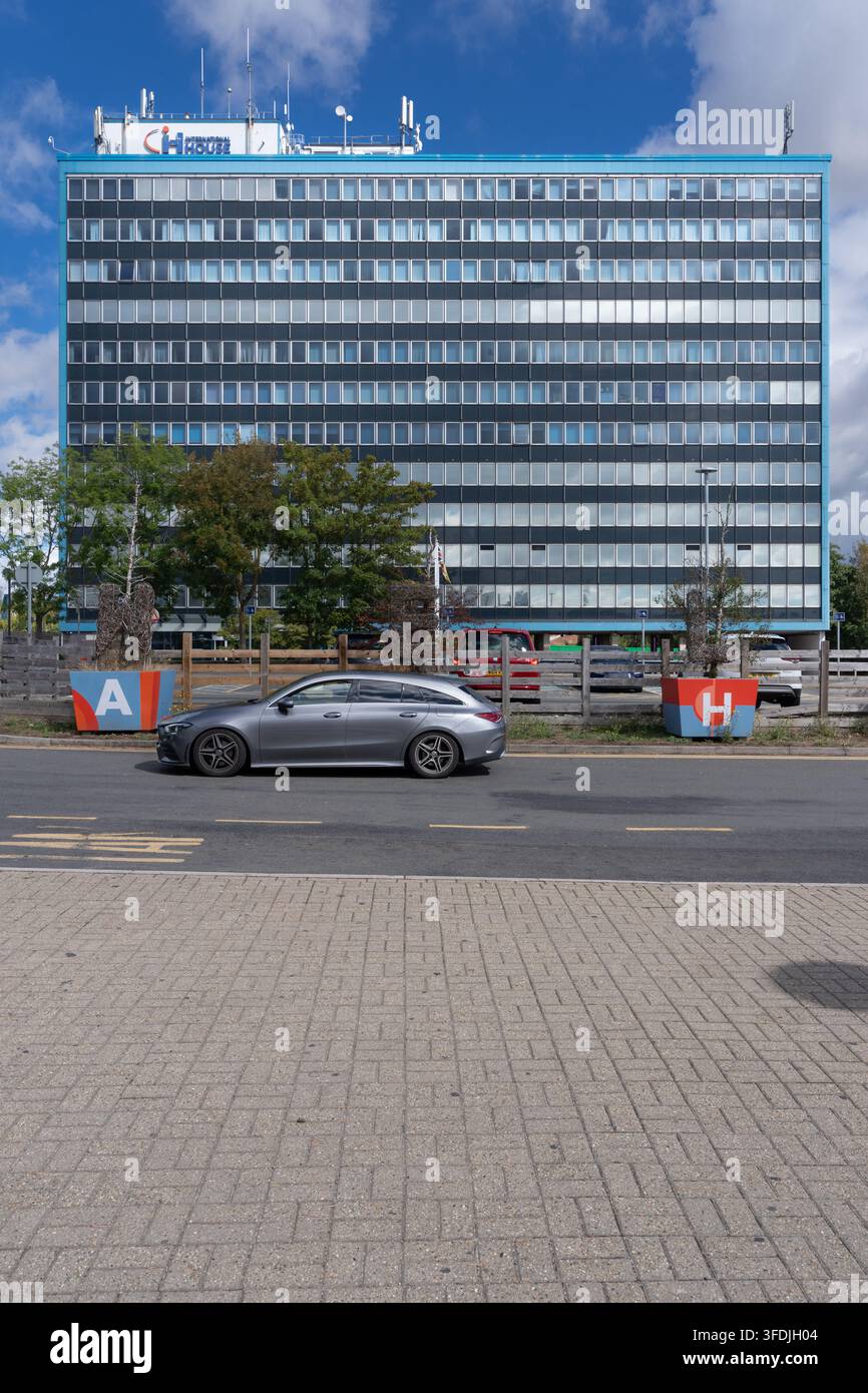 Un'auto grigia passa davanti all'International House, un importante punto di riferimento per gli uffici ad Ashford Foto Stock