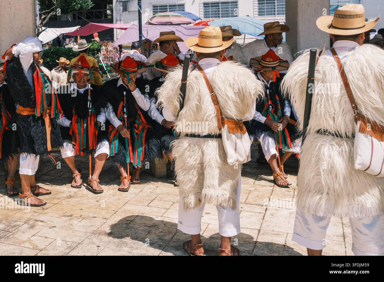 Chamula, Chiapas, Messico - 22 ottobre 2023: Vista di uomini maya tzotzil che indossano tuniche tradizionali in pelle di pecora e cappelli con nastri colorati riuniti in un Foto Stock