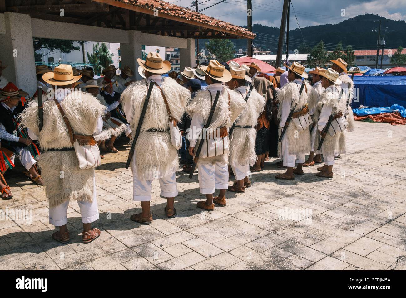 Chamula, Messico - 22 ottobre 2023: Vista di uomini Maya Tzotzil che indossano tuniche tradizionali di lana e cappelli di paglia radunati nella piazza del villaggio di Chamula, Ch Foto Stock