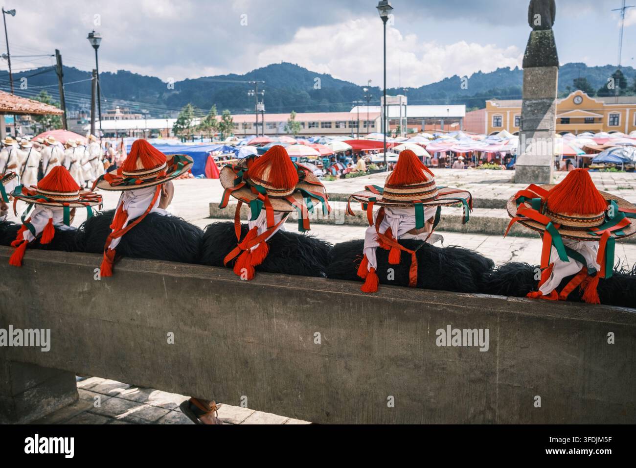 Chamula, Chiapas, Messico - 22 ottobre 2023: Vista di uomini Maya Tzotzil che indossano cappelli tradizionali con nappe e nastri rossi mentre sono seduti su un cemento Foto Stock