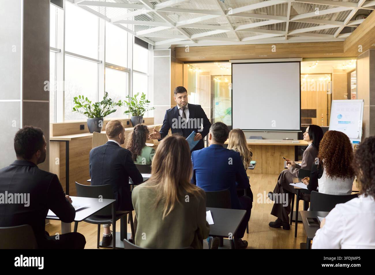 Seminar di formazione aziendale con team aziendale che ascolta un coach su uno schermo di proiezione Foto Stock