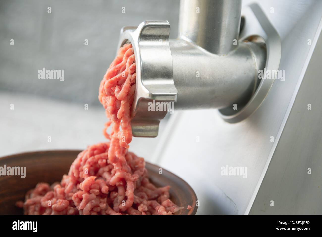 Macinacarni elettrico che trasforma il maiale crudo fresco in carne macinata Foto Stock