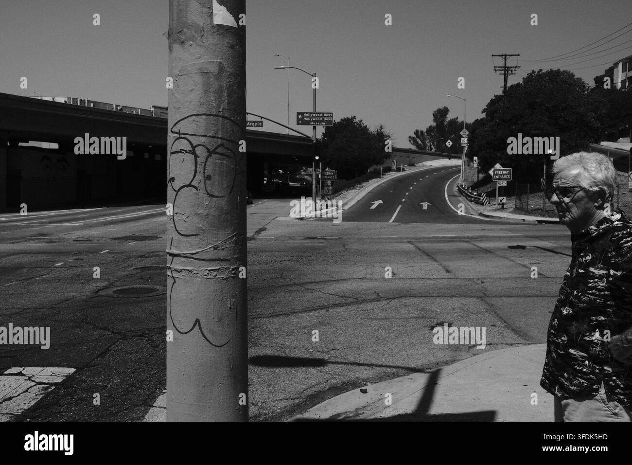 Palo di servizio eroso accanto a una strada curva di Los Angeles che porta alla US 101 con colline e vegetazione lungo la strada. Foto Stock
