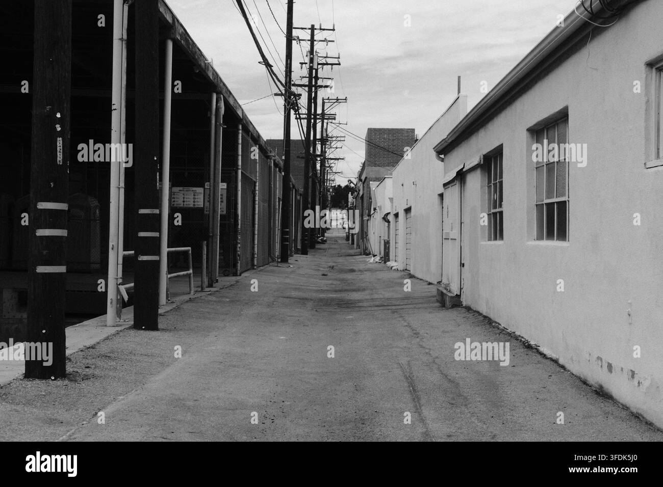 Vicolo stretto tra edifici industriali e commerciali in una scena urbana in bianco e nero della California del Sud Foto Stock