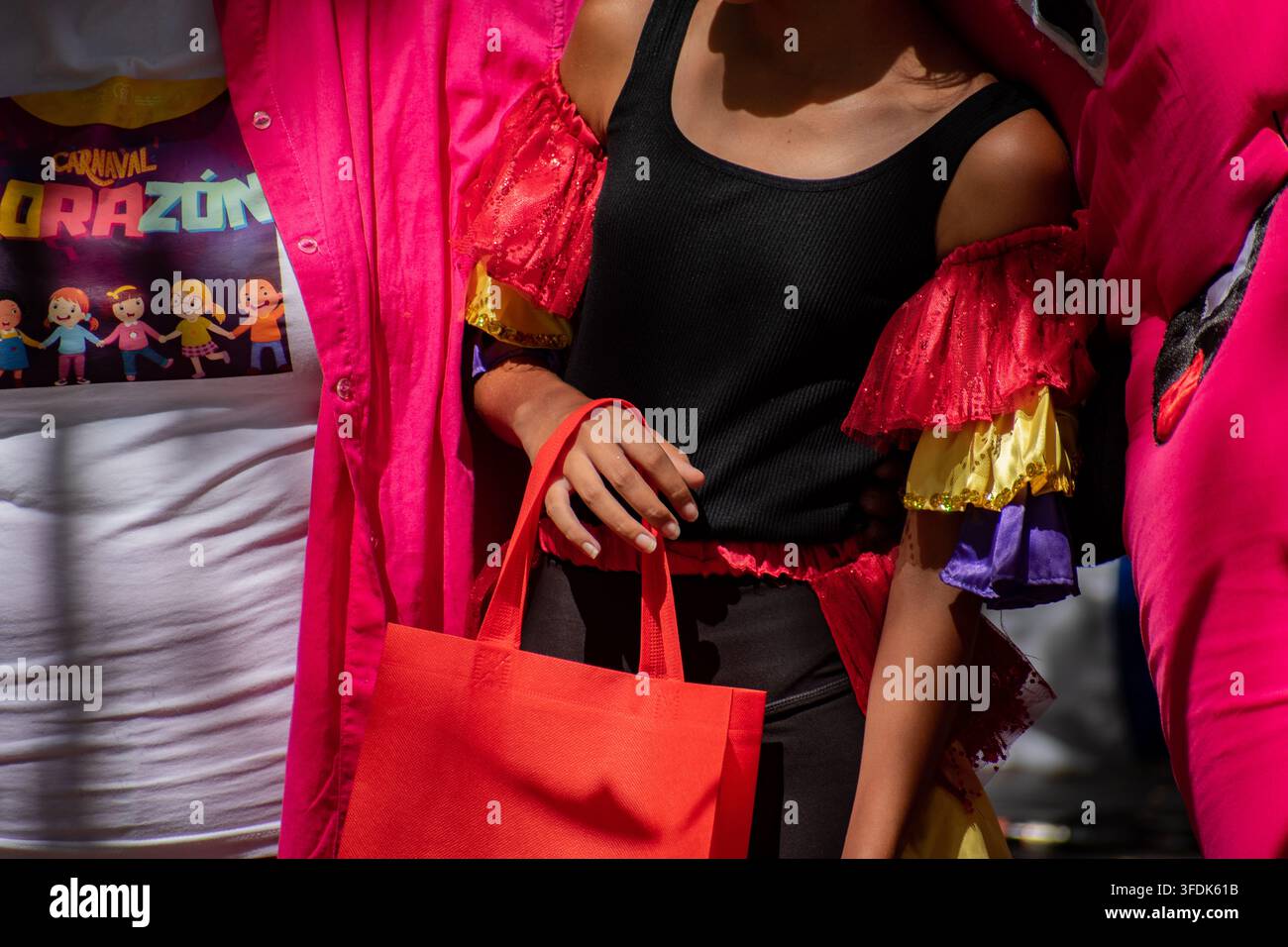 Primo piano di un artista in abito da carnevale colorato che tiene una borsa rossa durante l'evento El Carnavalito il 21 agosto 2026 a Ciego de Ávila, Cuba Foto Stock