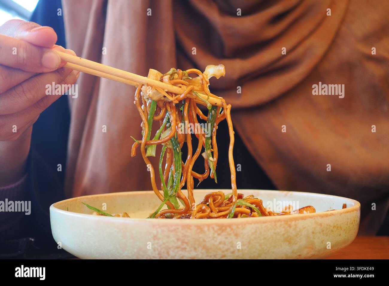 Mangiare noodles con le bacchette in un ristorante Foto Stock