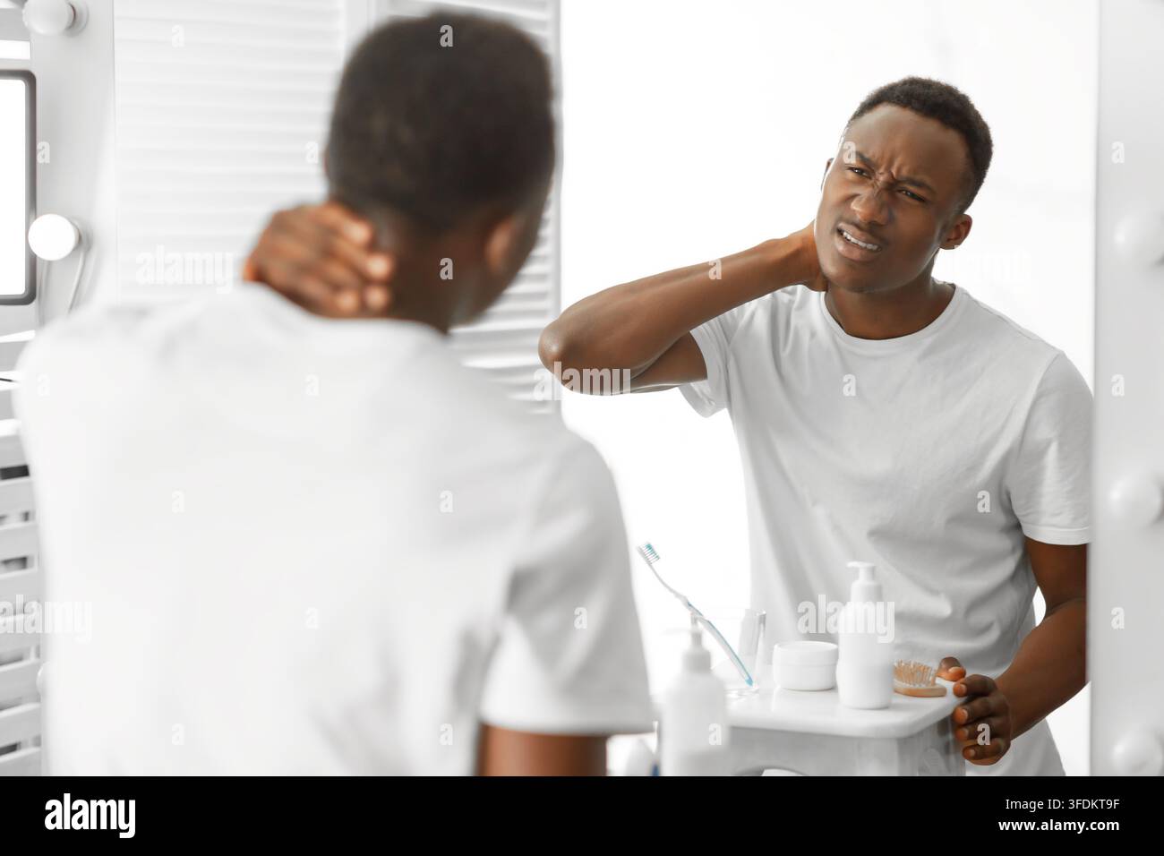 L'uomo africano che tocca il collo doloroso che soffre di dolore in bagno Foto Stock