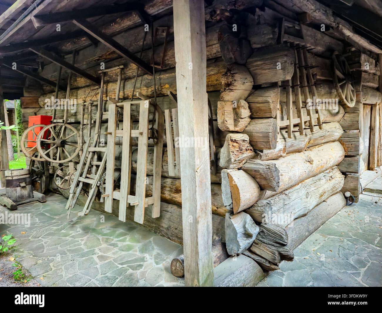 Una raccolta di strumenti in legno vintage e strutture rustiche in tronchi che evocano il patrimonio tradizionale ucraino e la vita rurale Foto Stock