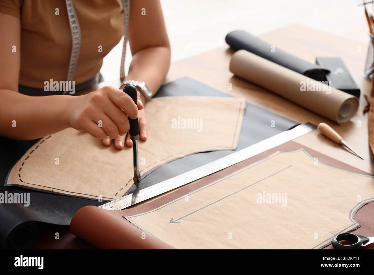 Design della moda e sartoria, sarta che utilizza una ruota tracciante su un modello di pelle a un tavolo da laboratorio per la produzione di abiti su misura e artigianali Foto Stock